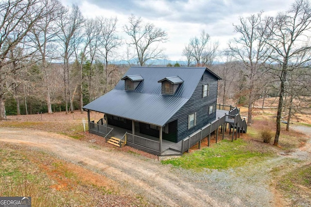 view of front of house featuring covered porch, dirt driveway, and metal roof