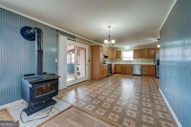 kitchen featuring a wood stove, stainless steel appliances, light countertops, light floors, and a sink