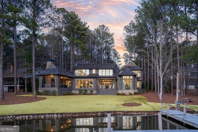 back of property at dusk with a lawn