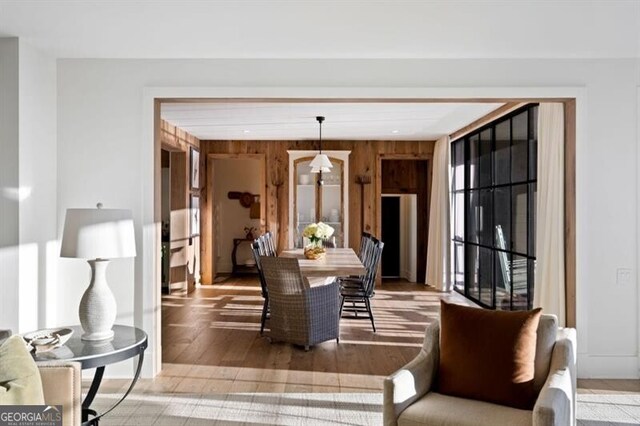 dining area with light wood finished floors and wood walls