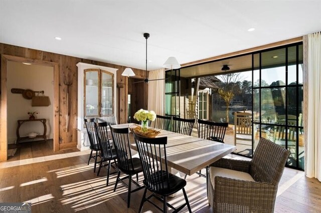 dining room featuring a wall of windows, wood finished floors, and wood walls