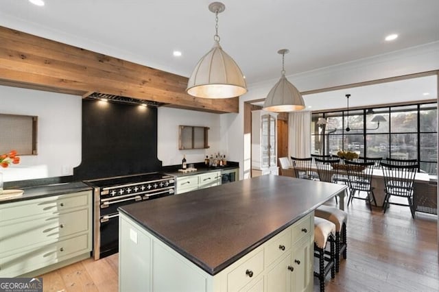 kitchen with dark countertops, a center island, decorative light fixtures, range with two ovens, and light wood-style flooring