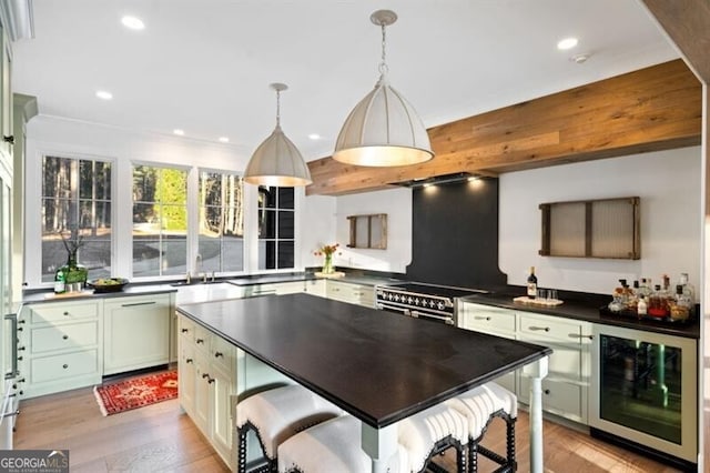 kitchen featuring dark countertops, wine cooler, stainless steel stove, light wood finished floors, and dishwashing machine