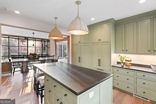 kitchen featuring dark countertops, visible vents, a kitchen island, green cabinets, and light wood-style floors