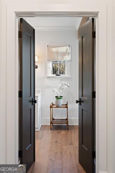 hall featuring crown molding, baseboards, and wood finished floors