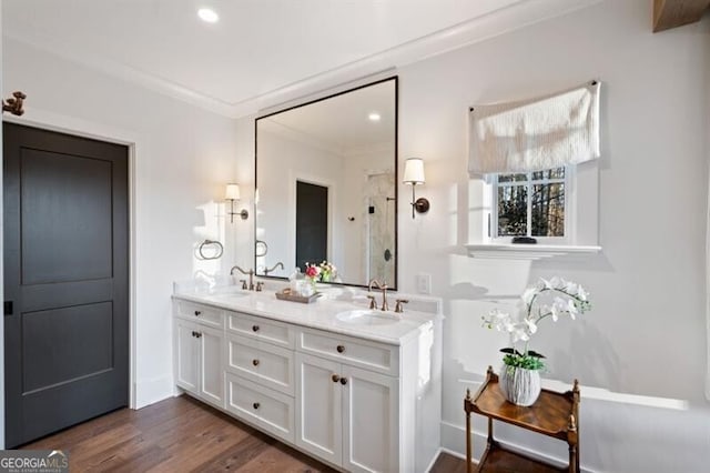 bathroom with crown molding, walk in shower, wood finished floors, and a sink