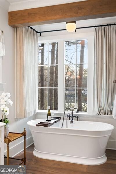 full bath with plenty of natural light, a soaking tub, and wood finished floors