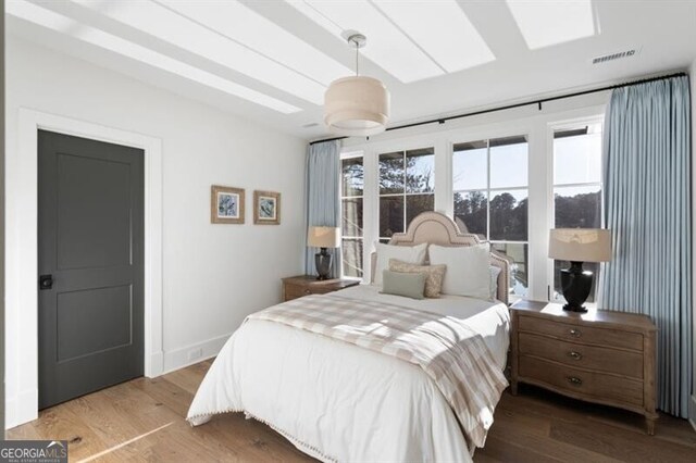 bedroom with wood finished floors, visible vents, and baseboards