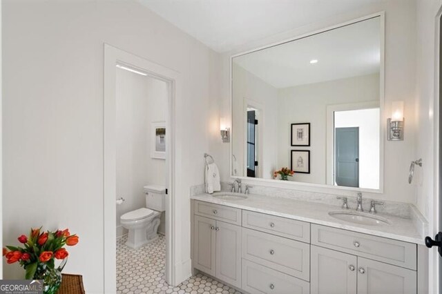 full bath with a sink, toilet, double vanity, and tile patterned floors