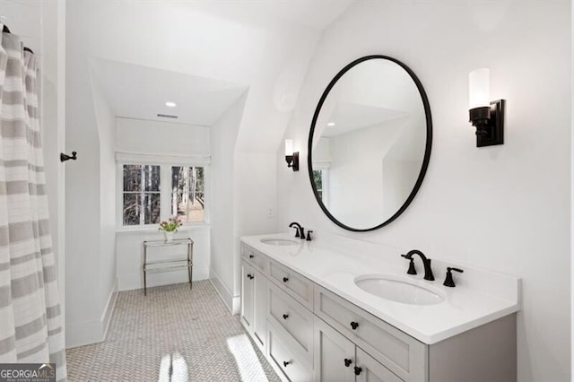 bathroom with tile patterned flooring, double vanity, baseboards, and a sink