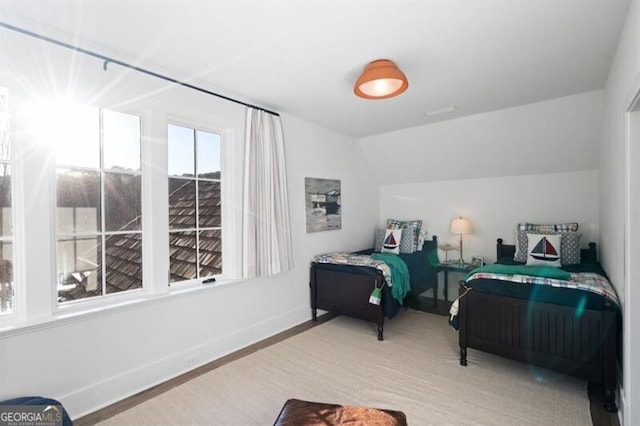 bedroom featuring lofted ceiling, wood finished floors, and baseboards