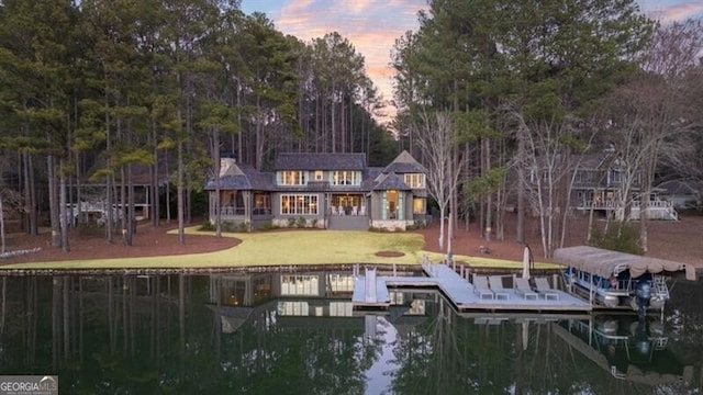 view of dock with a water view and a lawn