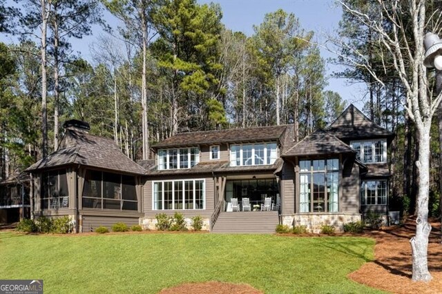 rear view of property featuring a yard and a sunroom