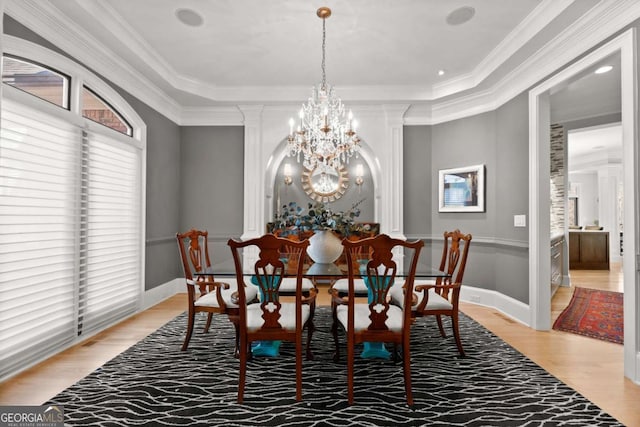 dining area with crown molding, baseboards, an inviting chandelier, light wood-style floors, and ornate columns