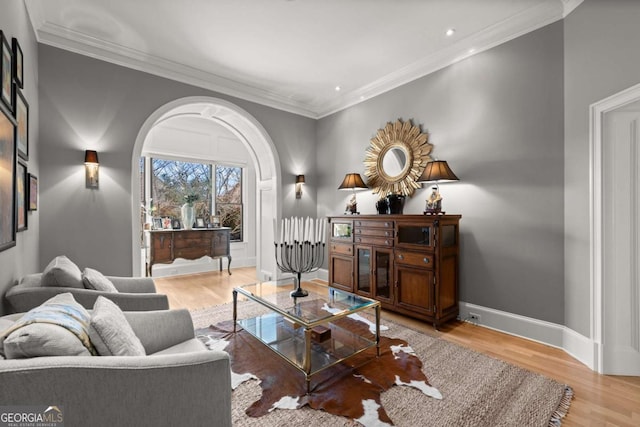 living area with wood finished floors, baseboards, recessed lighting, arched walkways, and crown molding