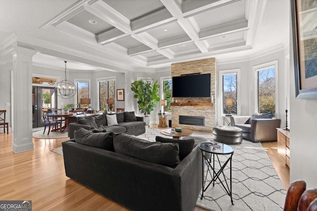 living room with beamed ceiling, a stone fireplace, light wood-style flooring, and ornate columns