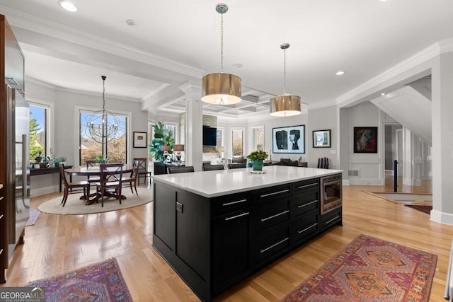 kitchen with dark cabinetry, stainless steel microwave, light wood-style floors, and light countertops