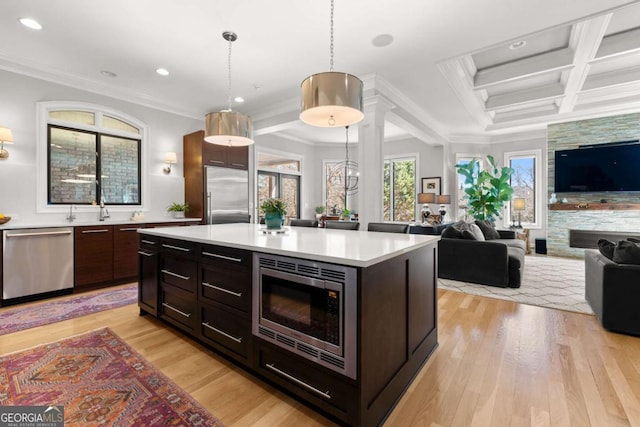 kitchen featuring built in appliances, light wood-style flooring, coffered ceiling, and light countertops