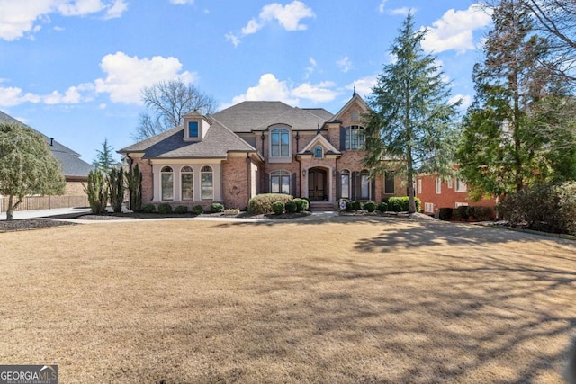 french provincial home featuring brick siding and a front lawn