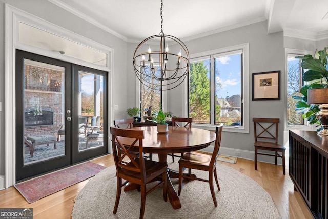 dining area featuring light wood-type flooring, baseboards, a chandelier, and crown molding