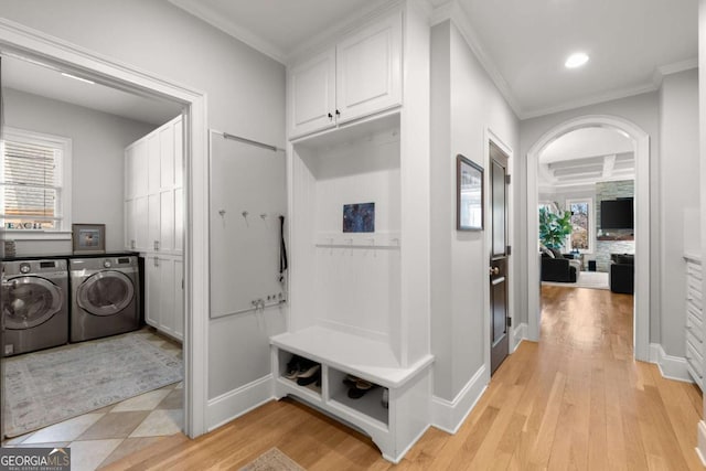 laundry room featuring light wood finished floors, cabinet space, crown molding, and separate washer and dryer