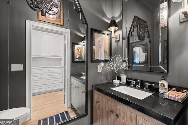 bathroom featuring toilet, vanity, crown molding, and wood finished floors