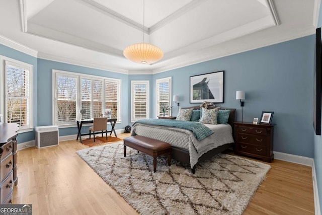 bedroom featuring crown molding, light wood-type flooring, a raised ceiling, and baseboards