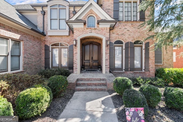 property entrance featuring french doors and brick siding