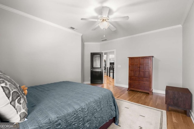 bedroom featuring visible vents, ornamental molding, baseboards, and wood finished floors