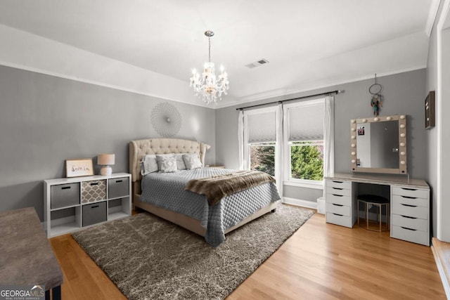 bedroom with baseboards, visible vents, light wood-style flooring, ornamental molding, and a chandelier