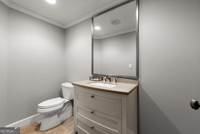 half bathroom with visible vents, toilet, ornamental molding, wood finished floors, and vanity