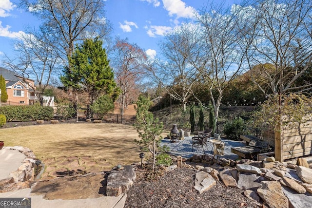 view of yard featuring a patio area, fence, and a fire pit