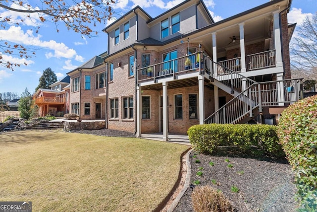 back of property with brick siding, stucco siding, stairs, and a yard