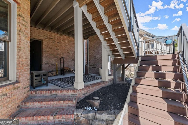 exterior space featuring brick siding, a porch, and stairs