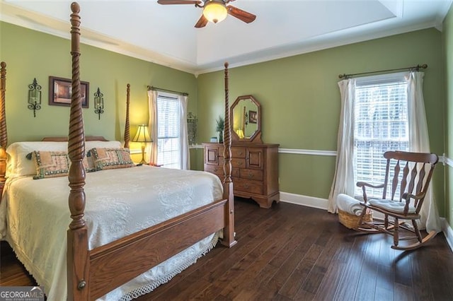 bedroom featuring hardwood / wood-style flooring, a ceiling fan, baseboards, a tray ceiling, and crown molding