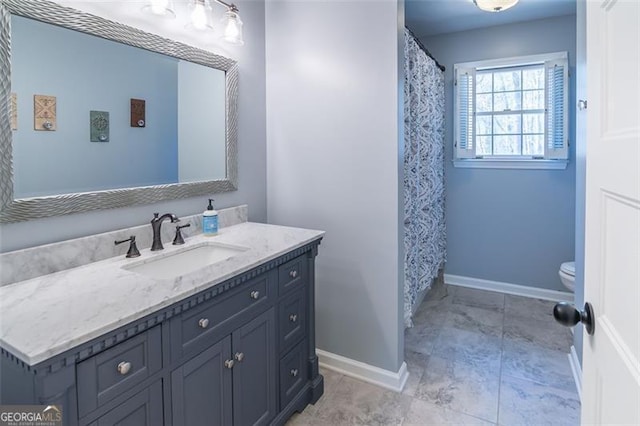 bathroom with toilet, vanity, and baseboards