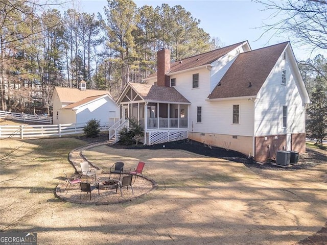 rear view of house featuring an outdoor fire pit, a shingled roof, a sunroom, a chimney, and fence