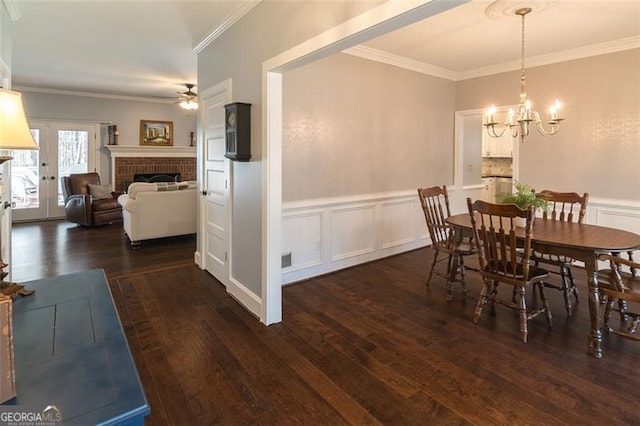 dining room with crown molding, wainscoting, a fireplace, and wood finished floors