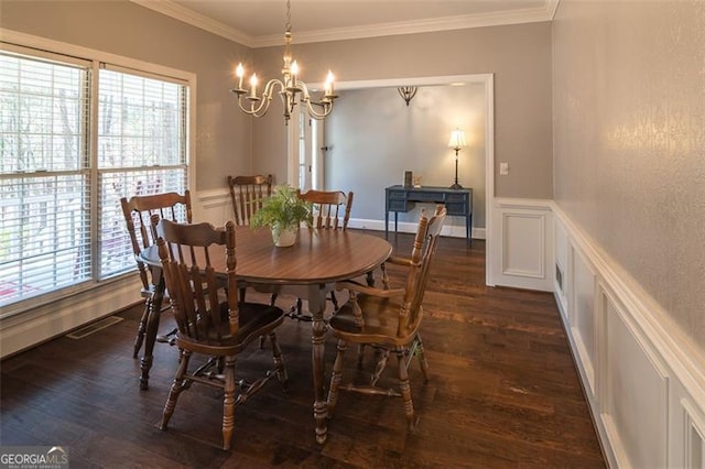 dining room with visible vents, dark wood-type flooring, an inviting chandelier, crown molding, and a decorative wall