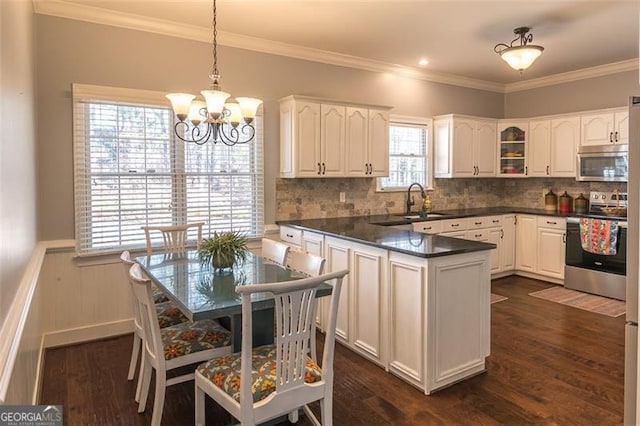 kitchen featuring appliances with stainless steel finishes, dark countertops, a wainscoted wall, and dark wood-type flooring