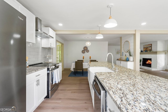 5985 Lakeside Ct, Gainesville, GA 30506 - kitchen with appliances with stainless steel finishes, wall chimney exhaust hood, light wood finished floors, white cabinets, and recessed lighting