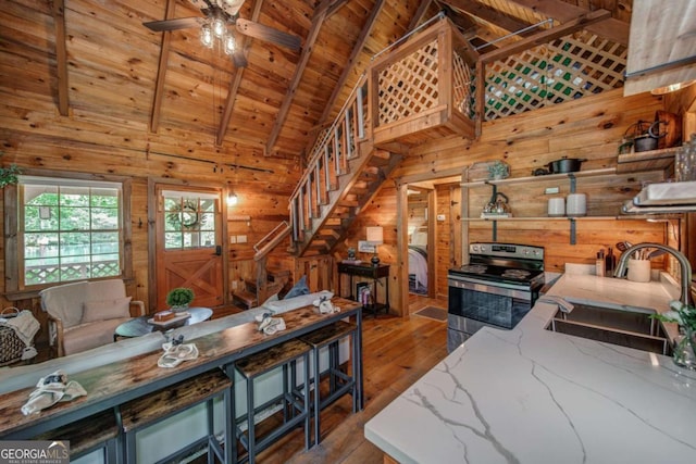 living area with wood ceiling, wooden walls, hardwood / wood-style floors, and beamed ceiling