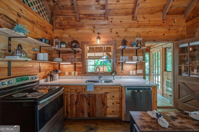 kitchen with lofted ceiling with beams, wood walls, a sink, appliances with stainless steel finishes, and open shelves