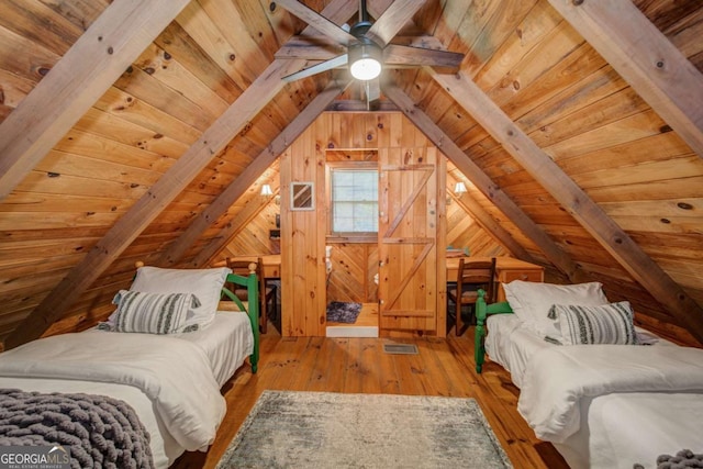 bedroom with lofted ceiling with beams, wooden ceiling, wooden walls, visible vents, and hardwood / wood-style floors