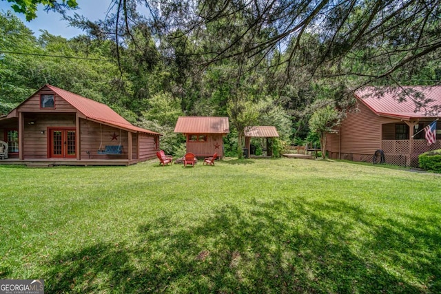 view of yard featuring an outbuilding, french doors, a wooden deck, and a storage unit