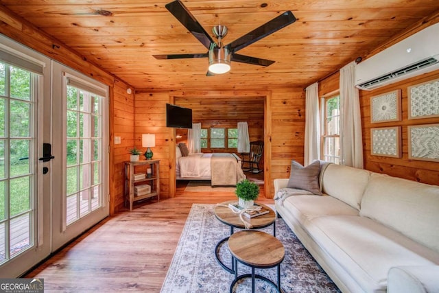 bedroom featuring a wall unit AC, access to outside, wood ceiling, and light wood-style flooring