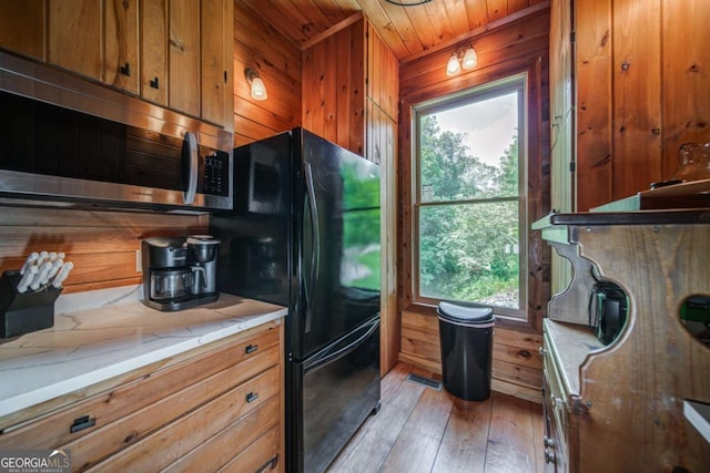 kitchen with wooden walls, visible vents, stainless steel microwave, brown cabinets, and light wood-style floors