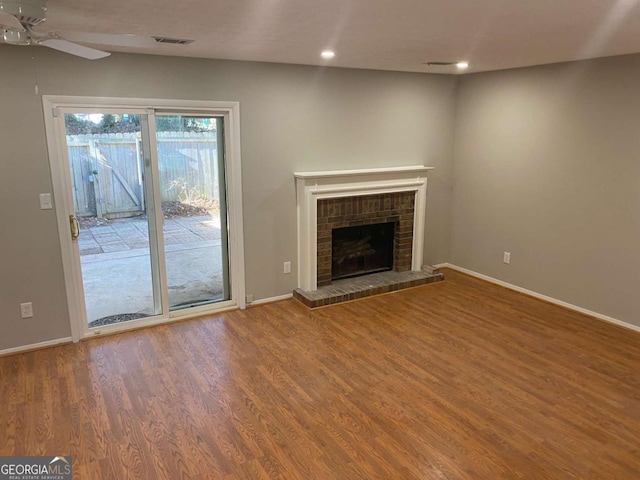 unfurnished living room featuring baseboards, a fireplace, visible vents, and wood finished floors