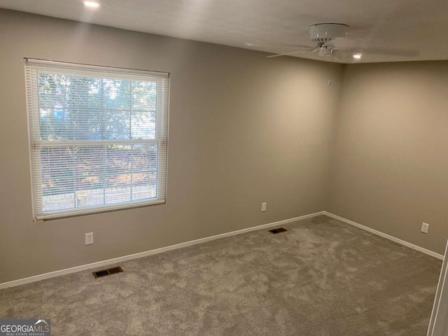 unfurnished room featuring ceiling fan, carpet floors, visible vents, and baseboards