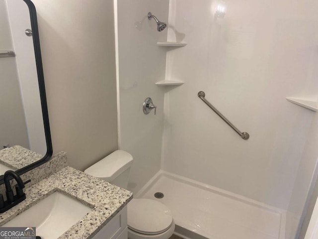 bathroom featuring a shower stall, toilet, and vanity